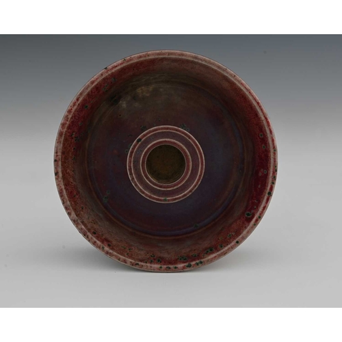 636 - Ruskin Pottery, a High Fired candle holder, 1931, flared circular dish form with central conical sco... 