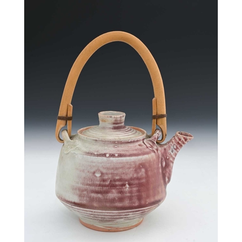 689 - Mary Rich (British, 1940-2022), a stoneware cane-handled teapot and cover, decorated with a pale whi... 