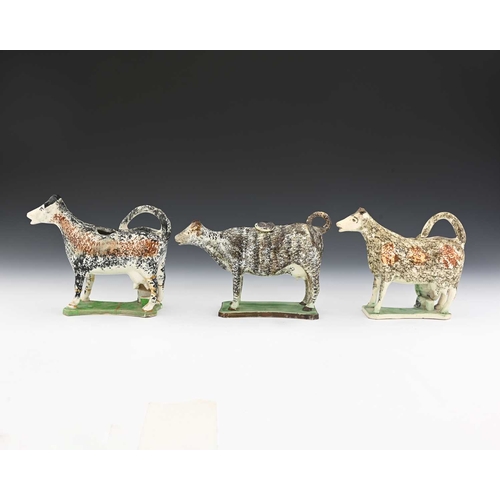 745 - Three 19th century Prattware sponge decorated pottery cow creamers, modelled on platform bases, two ... 