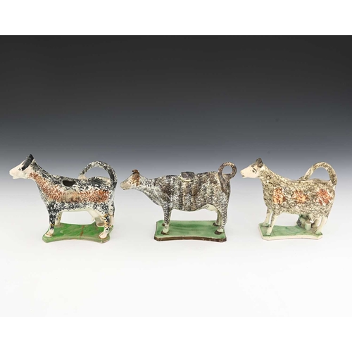 745 - Three 19th century Prattware sponge decorated pottery cow creamers, modelled on platform bases, two ... 