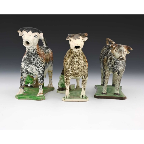 745 - Three 19th century Prattware sponge decorated pottery cow creamers, modelled on platform bases, two ... 