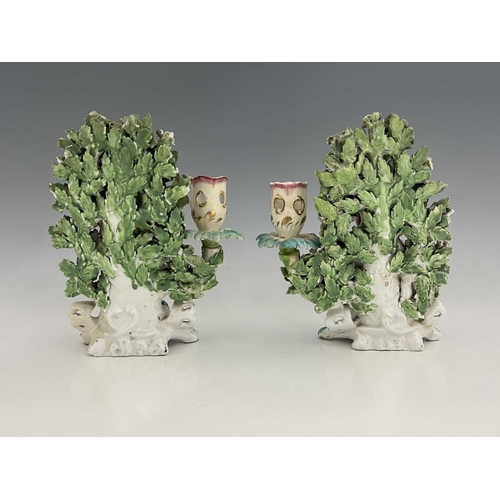 768 - A pair of Derby porcelain shepherd and shepherdess figural candlesticks, circa 1770, bocage backed, ... 