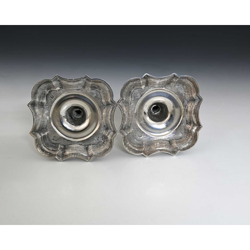 63 - A pair of George II silver cast candlesticks, each on a shaped stepped square base, with baluster st... 