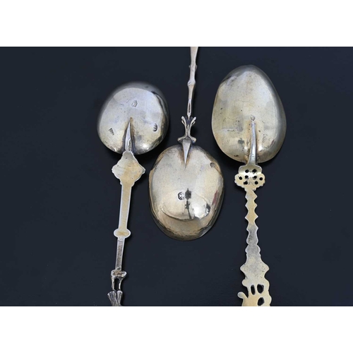 71 - Three Continental silver-coloured metal apostle-style spoons, each with a cast stem, surmounted by a... 