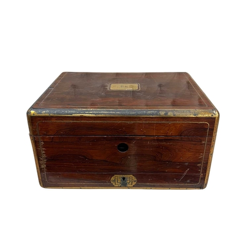 75 - An early Victorian rosewood and brass bound dressing case, the brass lift-out carrying handles to ei... 