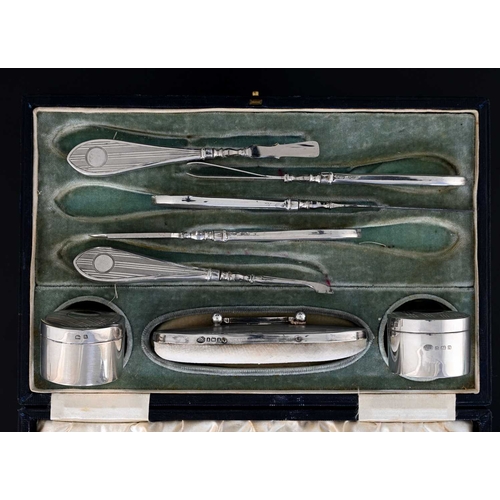 78 - A George V silver cased manicure set, comprising a pair of rouge pots, nail buff, and manicure tools... 