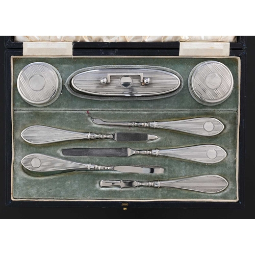 78 - A George V silver cased manicure set, comprising a pair of rouge pots, nail buff, and manicure tools... 