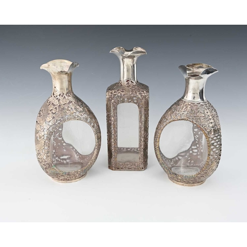 83 - China. Three Chinese silver overlay decanters, the casements of each pierced and decorated with drag... 