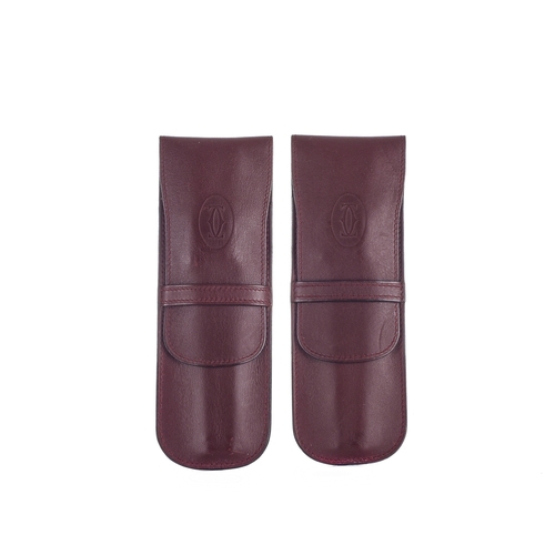 308 - Cartier, two Bordeaux leather pen cases, crafted from smooth burgundy leather, featuring front embos... 