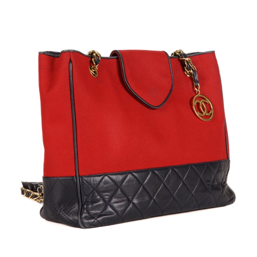 330 - Chanel, a Bicolour CC Charm tote, designed with a red canvas exterior with a quilted navy blue leath... 