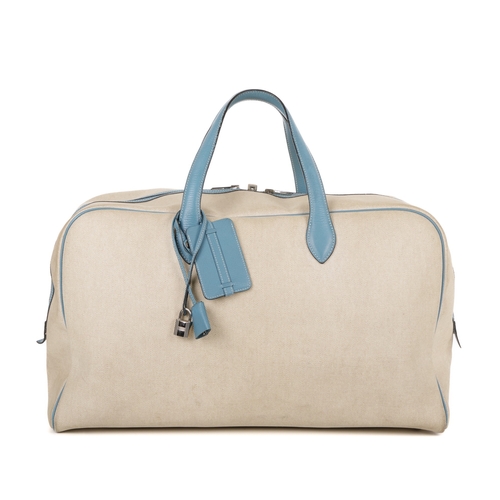 391 - Hermes, a 2000 toile Victora GM 50 travel bag, crafted from cream toile canvas with blue leather tri... 