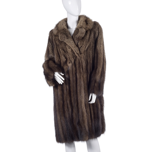 510 - A knee-length raccoon fur coat, fully stranded, featuring a notched lapel collar, hook and eye faste... 