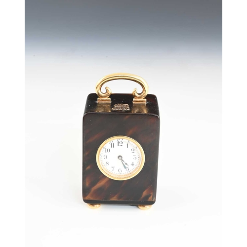 103 - A tortoiseshell travel clock with gold case components, dial with black Arabic numerals and outer mi... 