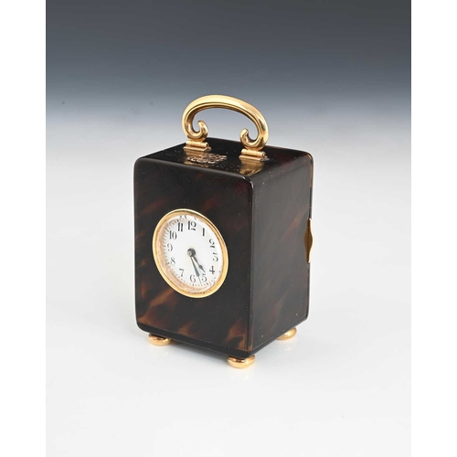 103 - A tortoiseshell travel clock with gold case components, dial with black Arabic numerals and outer mi... 