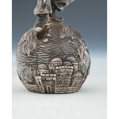 137 - Judaica, a twentieth-century silver-coloured metal figure, atop a sphere decorated in relief, inscri... 