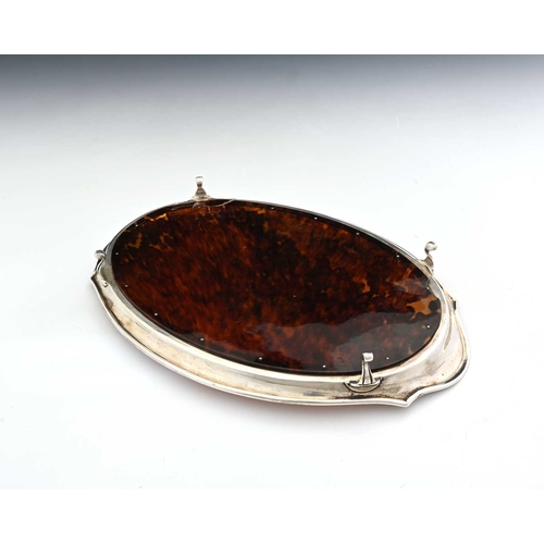 152 - A George V silver and tortoiseshell dressing table tray, of oval form with a shaped, flared rim, the... 