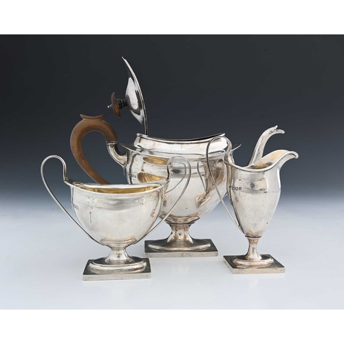 176 - An Edwardian silver three-piece tea set, comprising teapot with wood handle and finial, milk jug, an... 