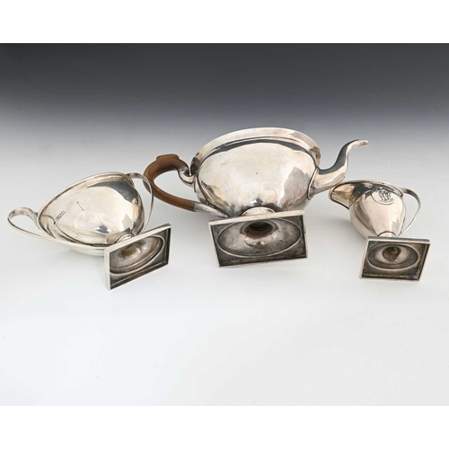 176 - An Edwardian silver three-piece tea set, comprising teapot with wood handle and finial, milk jug, an... 