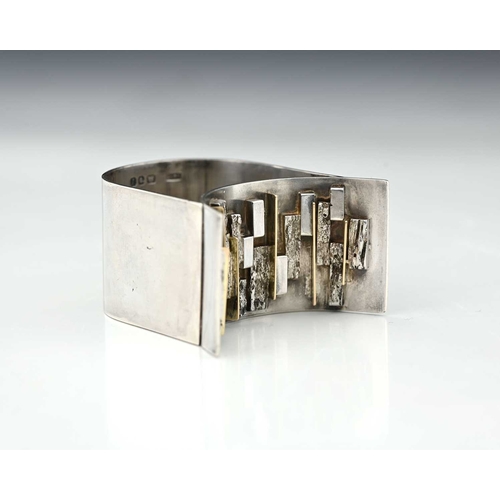 227 - A Modernist silver and parcel gilt napkin ring, LC-F, London 1966, double arched band form with text... 