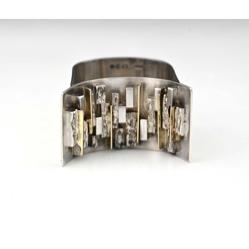 227 - A Modernist silver and parcel gilt napkin ring, LC-F, London 1966, double arched band form with text... 