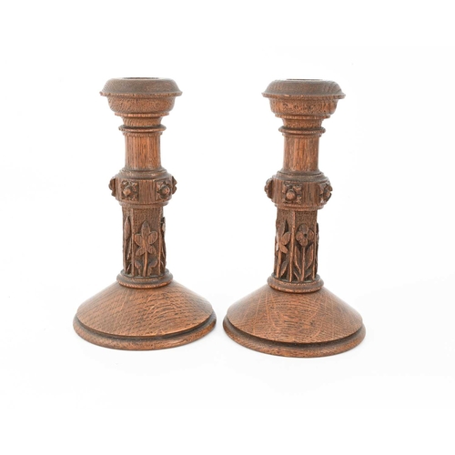 266 - A pair of Gothic Revival carved oak candlesticks, column form with floral motifs to the lower sectio... 