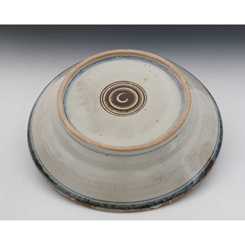 807 - Seth Cardew, a studio pottery dish, celadon ground ash glaze painted with a bird within foliate and ... 