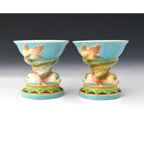 817 - A pair of Minton majolica pedestal dishes, of small proportions, shape 560, modelled as entwined dol... 