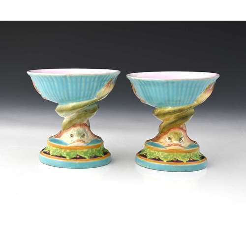 817 - A pair of Minton majolica pedestal dishes, of small proportions, shape 560, modelled as entwined dol... 