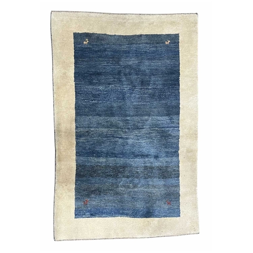 763 - A Gabbeh wool rug, blue with cream border, animal motifs to the corners, 266 by 170cm