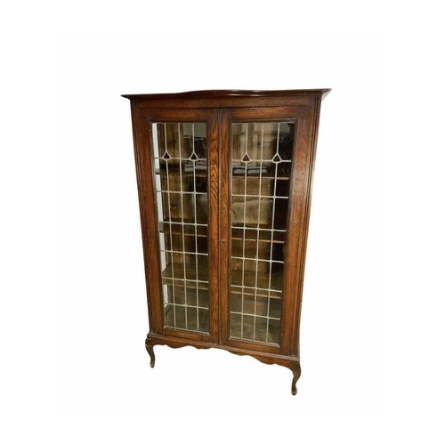 811 - An early 20th century oak display cabinet with leaded glass panels to the doors, holding three shelv... 