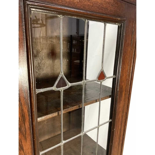 811 - An early 20th century oak display cabinet with leaded glass panels to the doors, holding three shelv... 