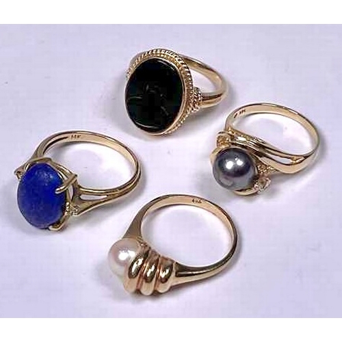 606 - Four gold coloured metal gem-set rings, to include a lapis lazuli and an onyx cabochon single-stone ... 