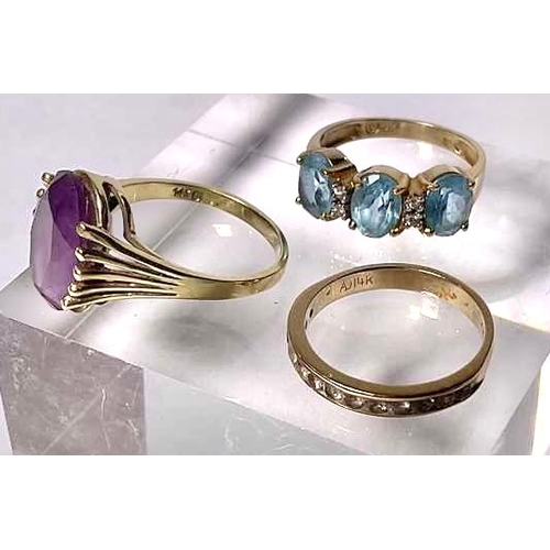 625 - Three gold coloured metal gem-set rings, to include a blue topaz three-stone ring, an amethyst singl... 