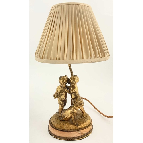 192 - A gilded metal table lamp, cast in the form of three putti with grapes, mounted on an ovoid pink har... 