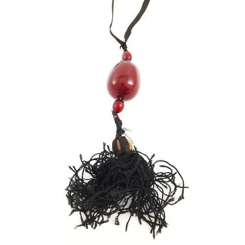 313 - An early 20th century bakelite pendant necklace, with a large bead, two smaller beads and tassel sus... 