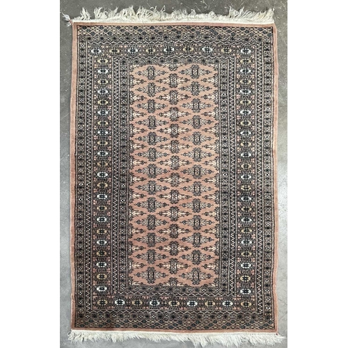 339 - A tribal/Oriental design wool rug, peach pink ground with beige and navy geometric pattern, approx 1... 