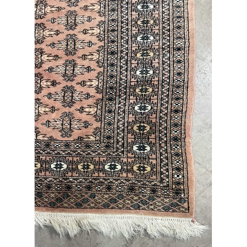 339 - A tribal/Oriental design wool rug, peach pink ground with beige and navy geometric pattern, approx 1... 