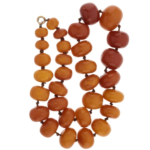 128 - A graduated natural amber bead necklace, with yellow metal clasp, beads measure approximately 22 to ... 