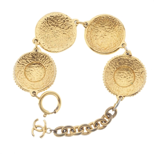 384 - Chanel, a vintage gold-tone coin bracelet, featuring four large domed coins decorated with Chanel's ... 