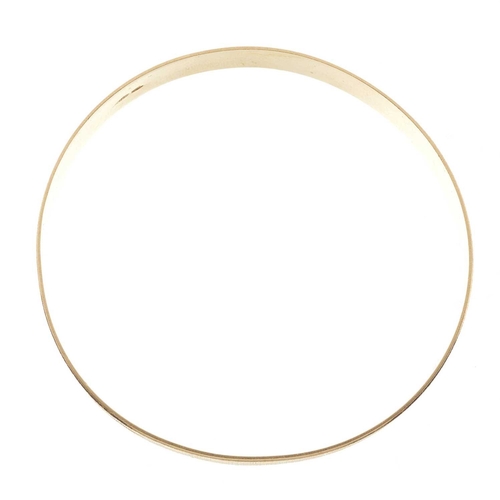 61 - An 18ct gold bangle bracelet, with engraved detail, foreign marks, stamped 750, inner diameter 6.6cm... 