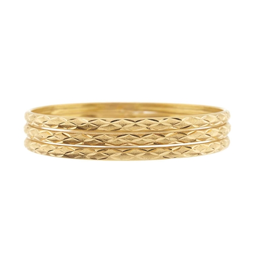 78 - Three high carat gold engraved bangle bracelets, Egyptian marks, inner diameters 6.4cm, 26.2g