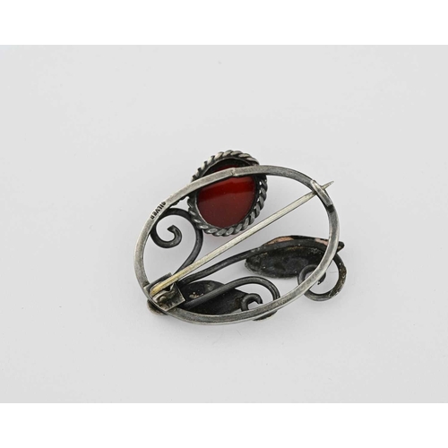 31 - Charles and Gladys Mumford, an Arts and Crafts silver and carnelian brooch, oval frame with coiled w... 