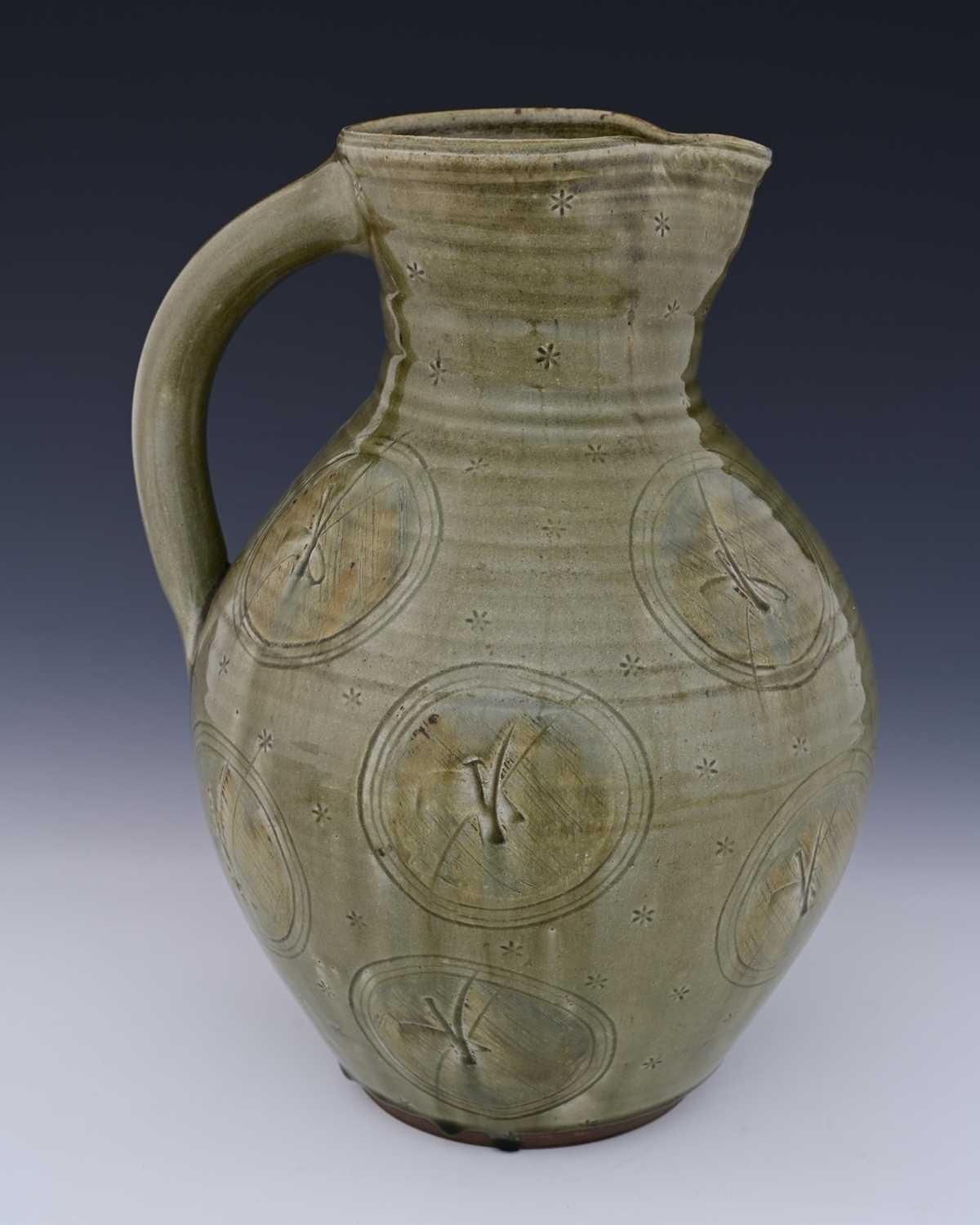 A large studio pottery jug, bulboud form, celadon glazed and decorated ...