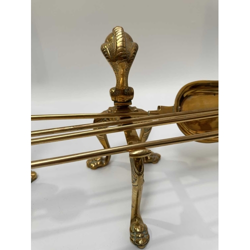 143 - A brass companion set and fire dogs, the poker, tongs and shovel all with clawed bird feet holding b... 