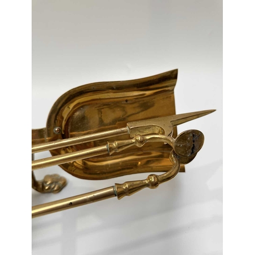 143 - A brass companion set and fire dogs, the poker, tongs and shovel all with clawed bird feet holding b... 