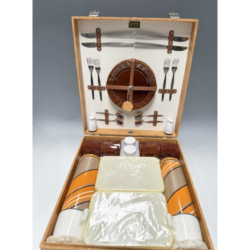 196 - A mid century, as new 'Brexton' picnic set for four, to include: a case with two orange, brown and b... 