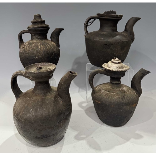 210 - A collection of Tibetan domestic cooking vessels, four teapots with carved wood, metal and earthenwa... 