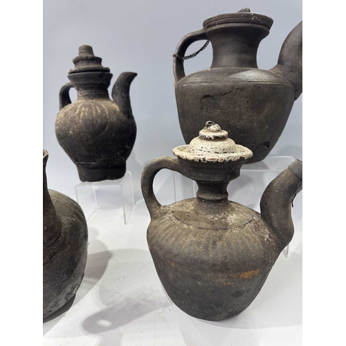 210 - A collection of Tibetan domestic cooking vessels, four teapots with carved wood, metal and earthenwa... 