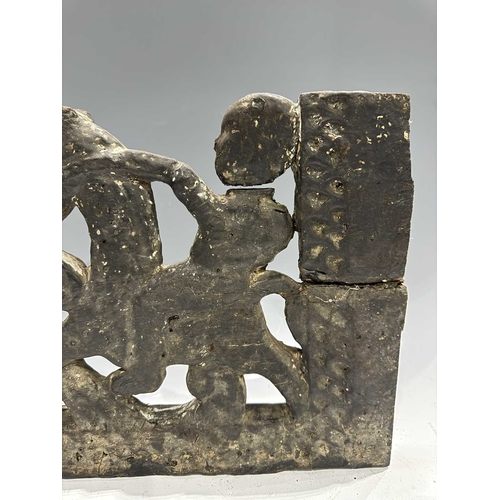 287 - A carved wood panel depicting a figure on horseback amongst a scrolling floriate background, tarred ... 