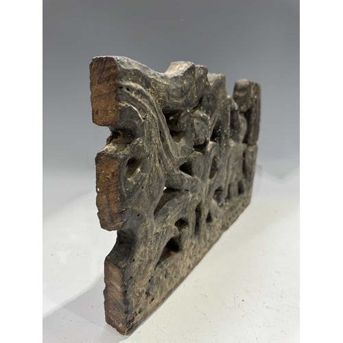 287 - A carved wood panel depicting a figure on horseback amongst a scrolling floriate background, tarred ... 